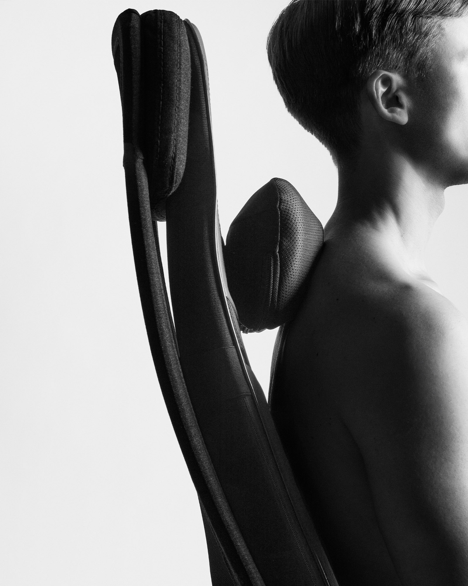 A monochrome side profile of a person using the Flowseat Pro for ergonomic neck and upper back support while seated.