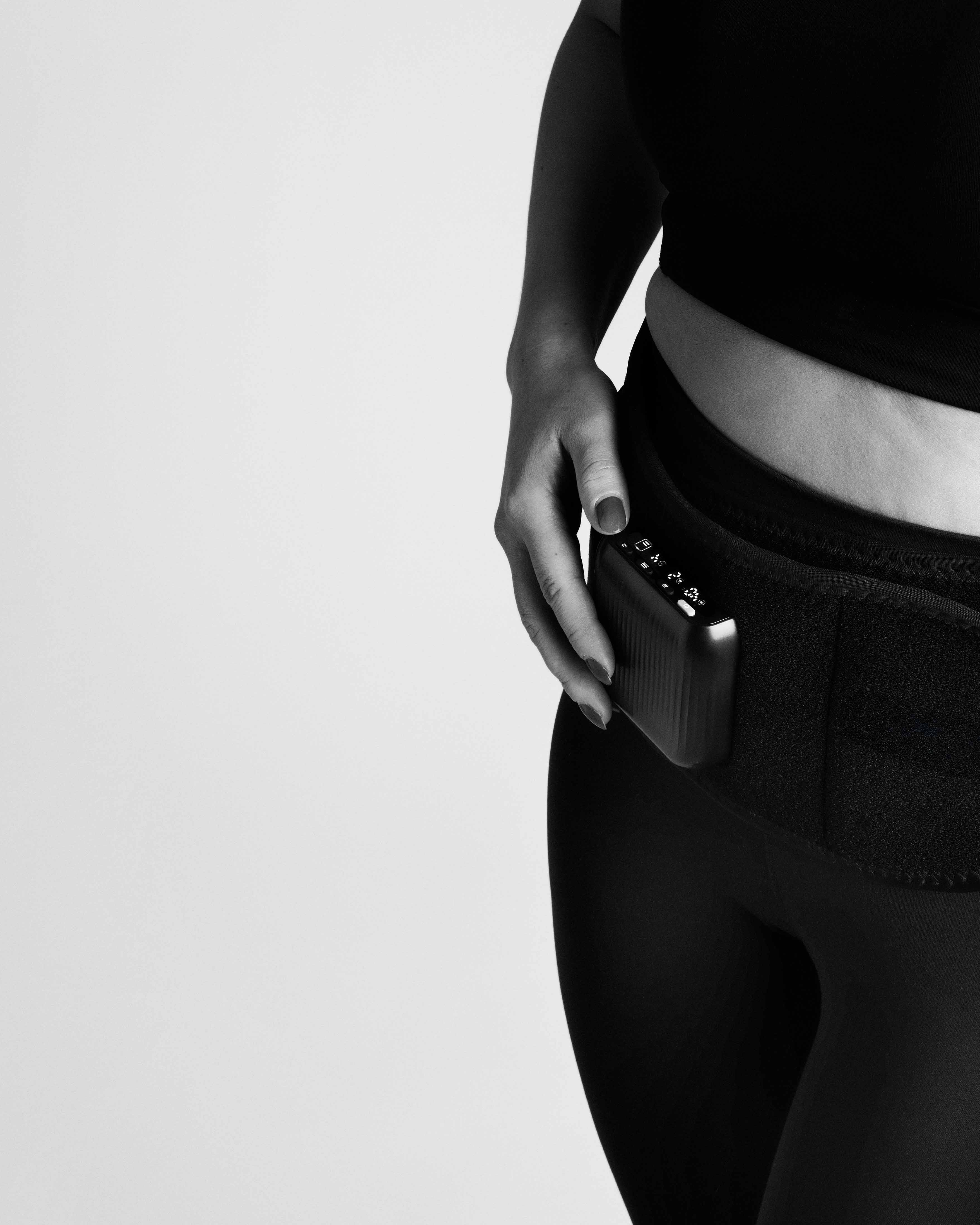 Monochromatic close-up of the Flowtherma Belt worn on the waist, highlighting the integrated control module.