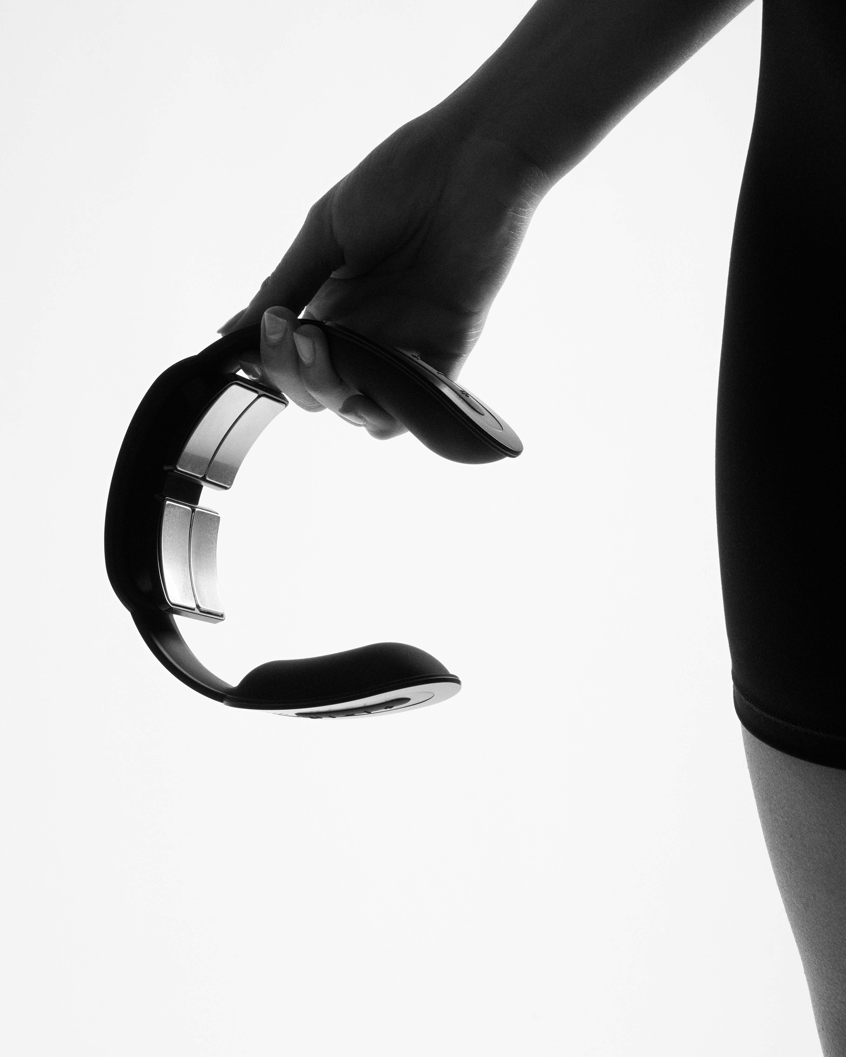 A hand holds the black Flowtens Neck Reuse, featuring contoured silver electrodes for targeted cervical stimulation.