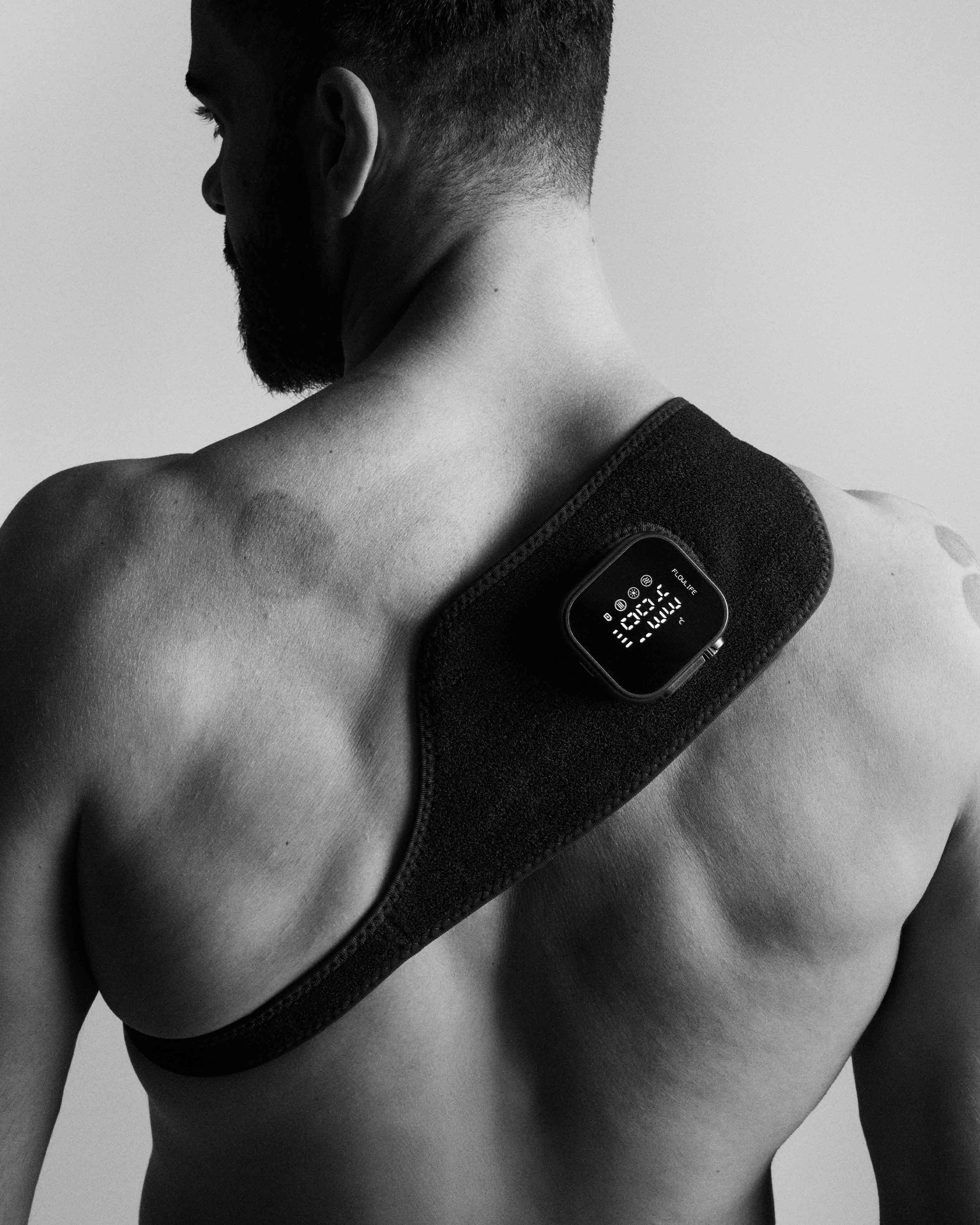 Flowtherma Spot applied to a man's upper back with a black fabric strap for focused thermal recovery.