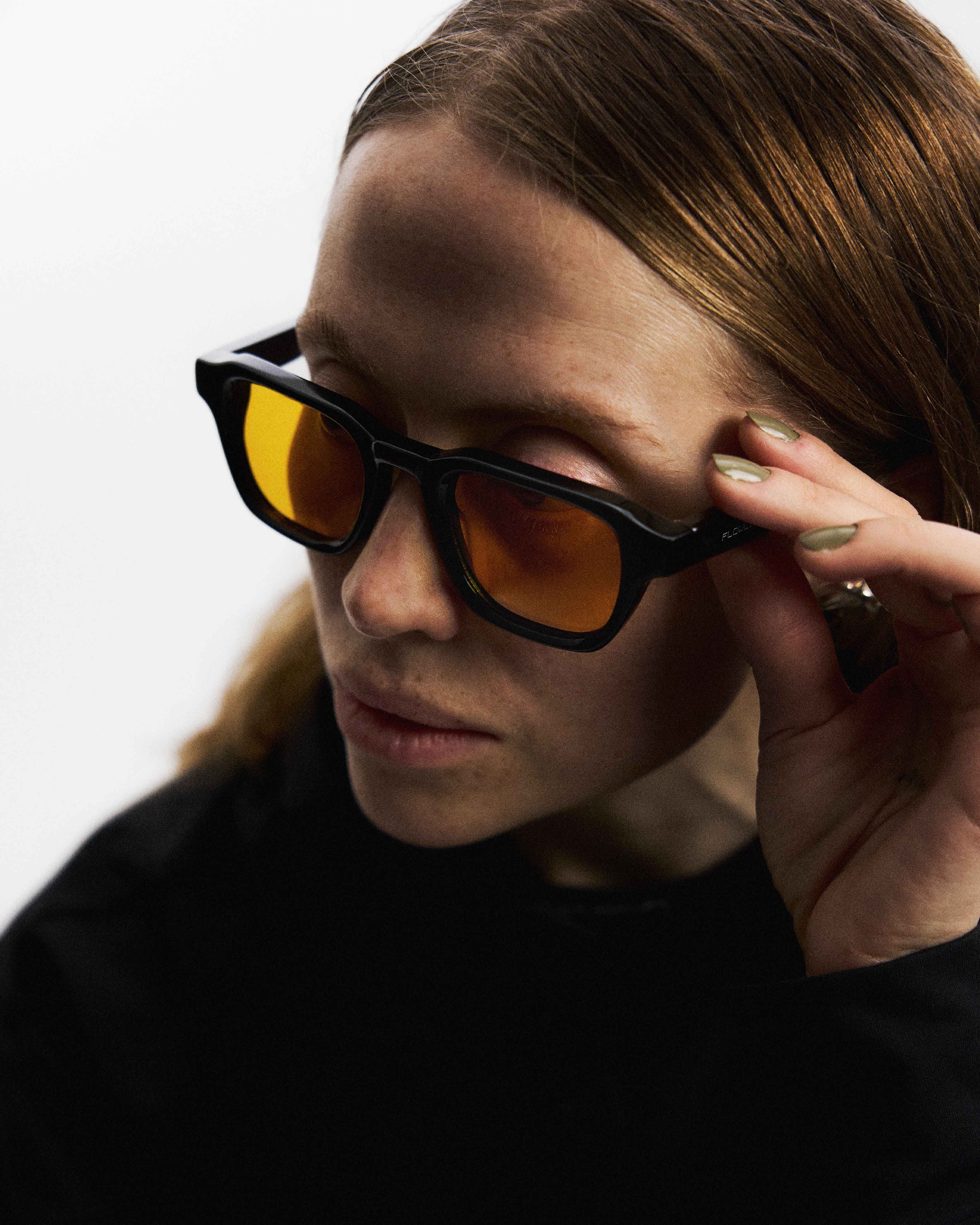 Närbild på kvinna som bär Flowglasses Day Sync 03 - Álvaro Edition med bärnstensfärgade linser som filtrerar blått dagsljus.