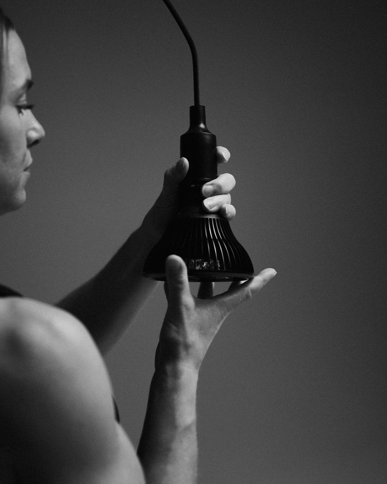 Flowlight Bulb 50 Six Waves held in two hands, showing the ridged black housing and integrated handheld socket.