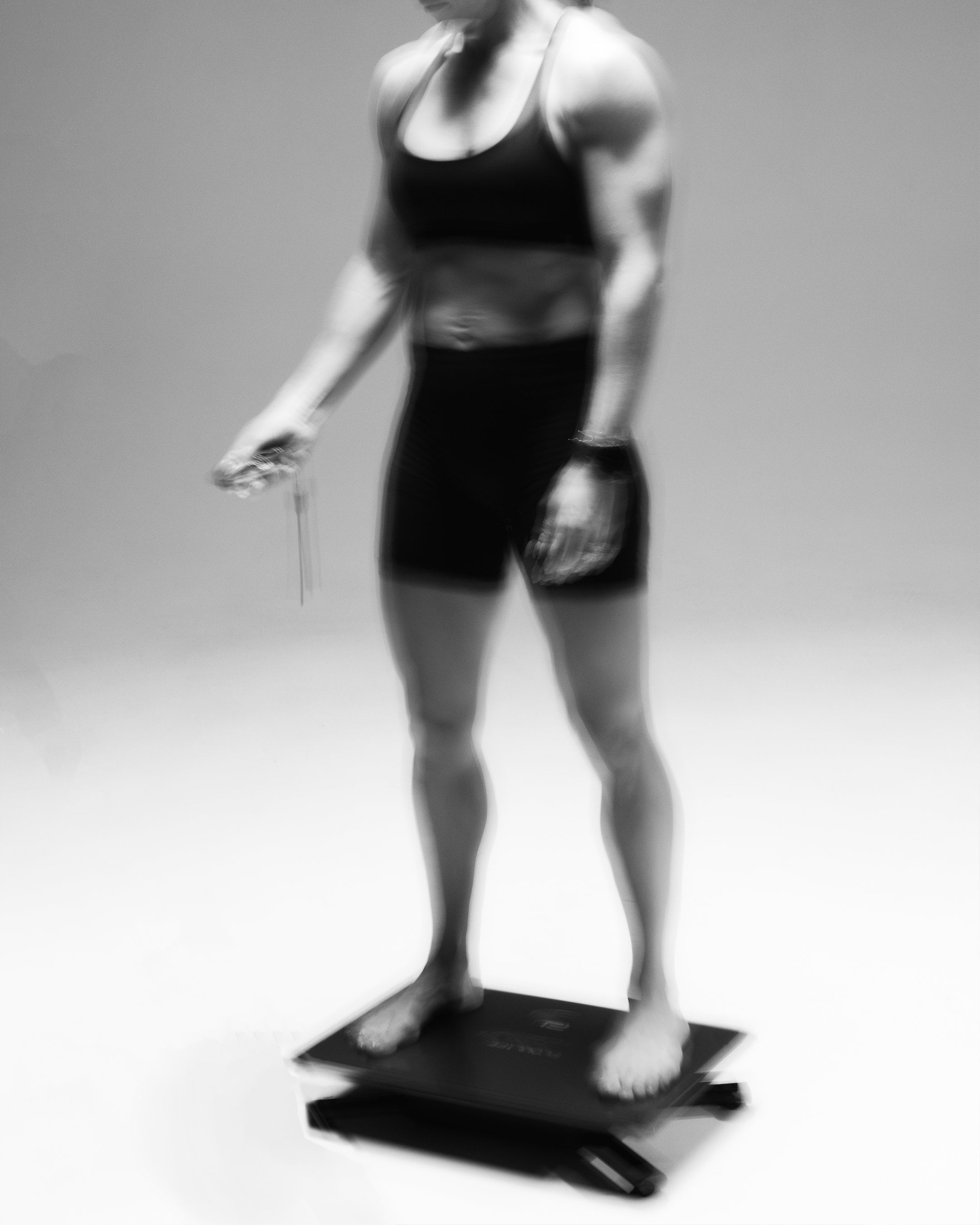 Woman standing barefoot on the Flowplate Vibe Pro holding the remote control.