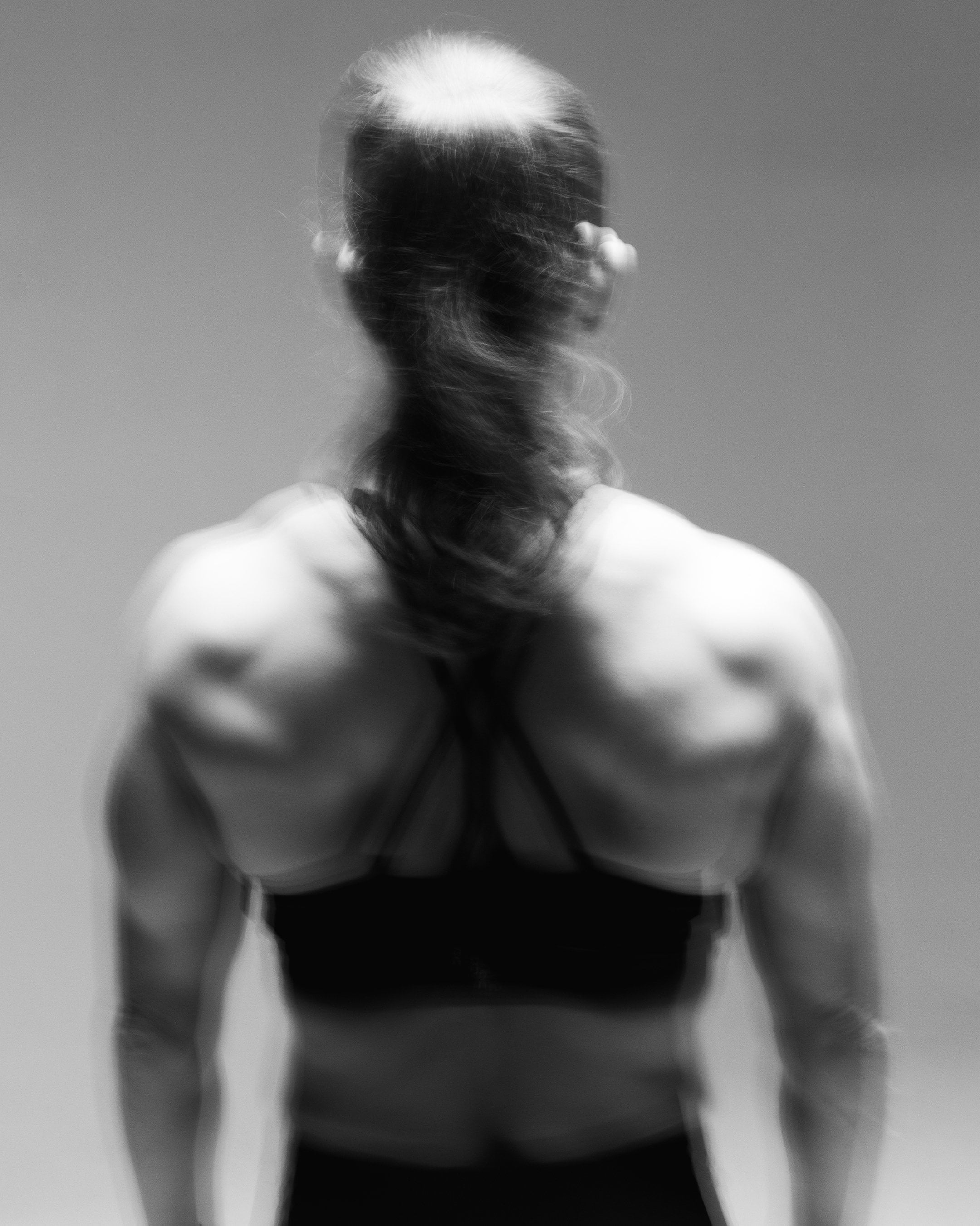 Woman seen from behind, back and shoulders in motion during a session on the Flowplate Vibe Pro.