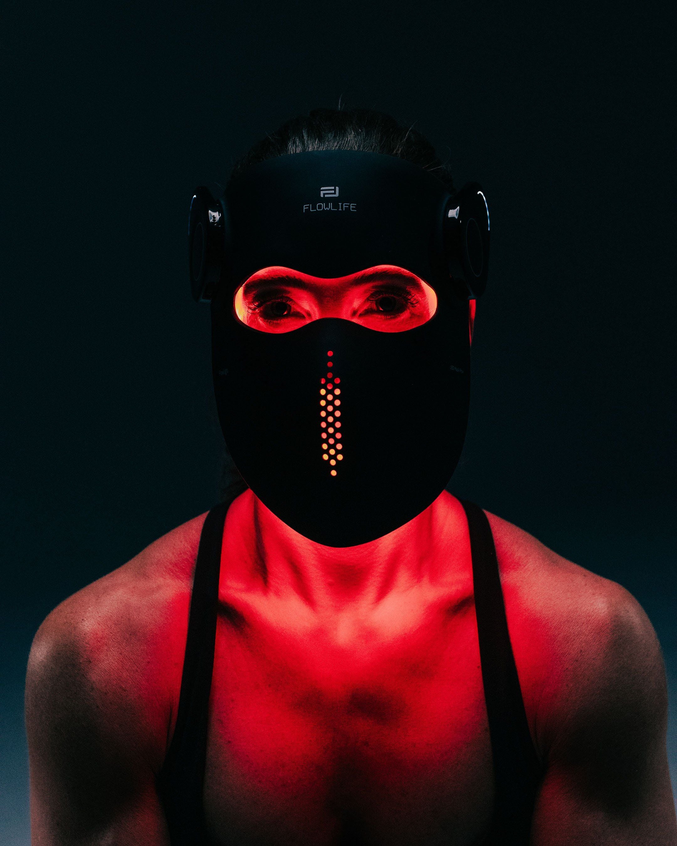 A woman facing the camera wearing the Flowlight LED Mask Pro+ during a red light therapy session.