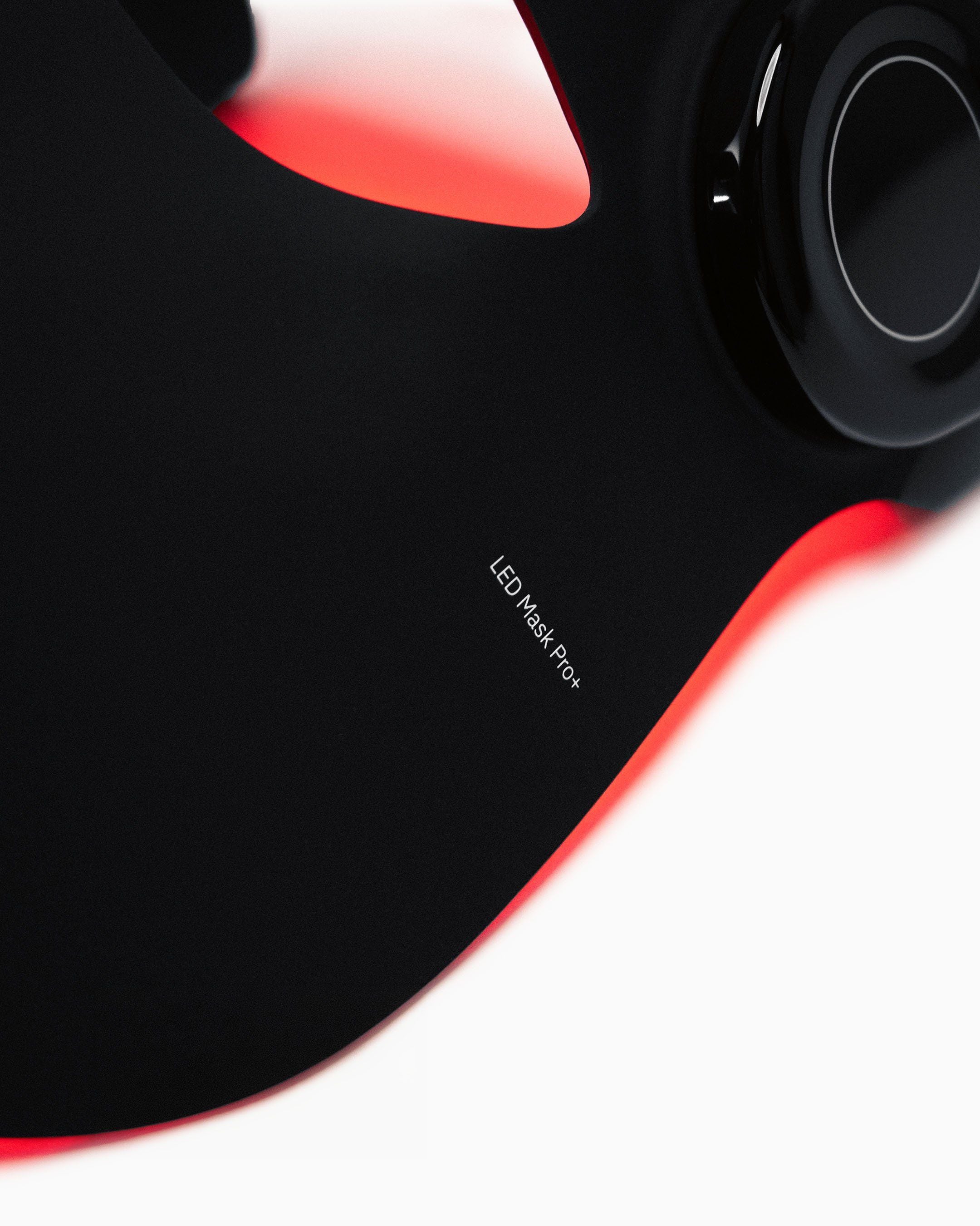 Close-up of the Flowlight LED Mask Pro+ showing the model name printed on the black silicone mask and the side control unit.