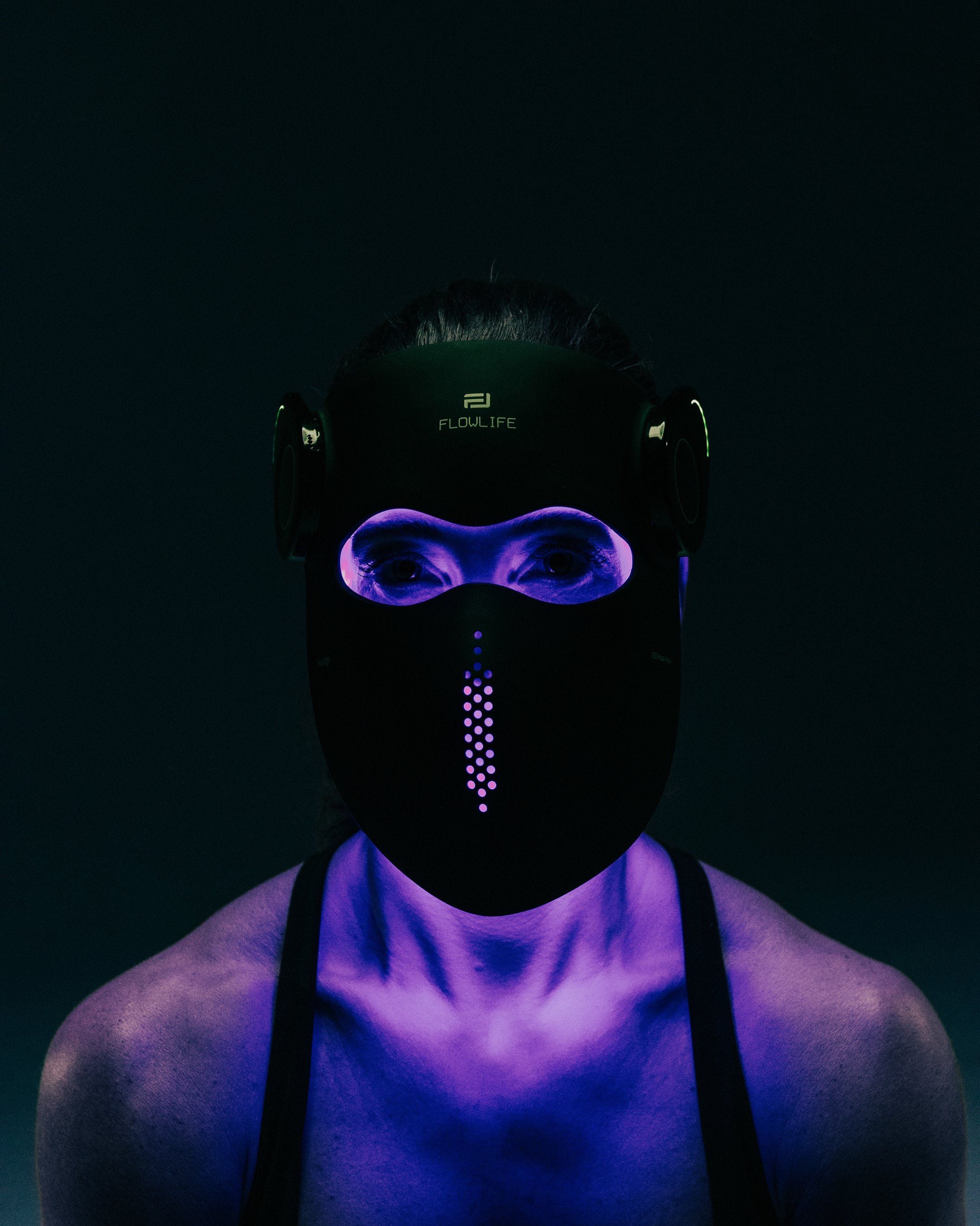 A person wearing the Flowlight Laser Mask Ultra+ in blue light mode, with blue light reflecting on the shoulders.