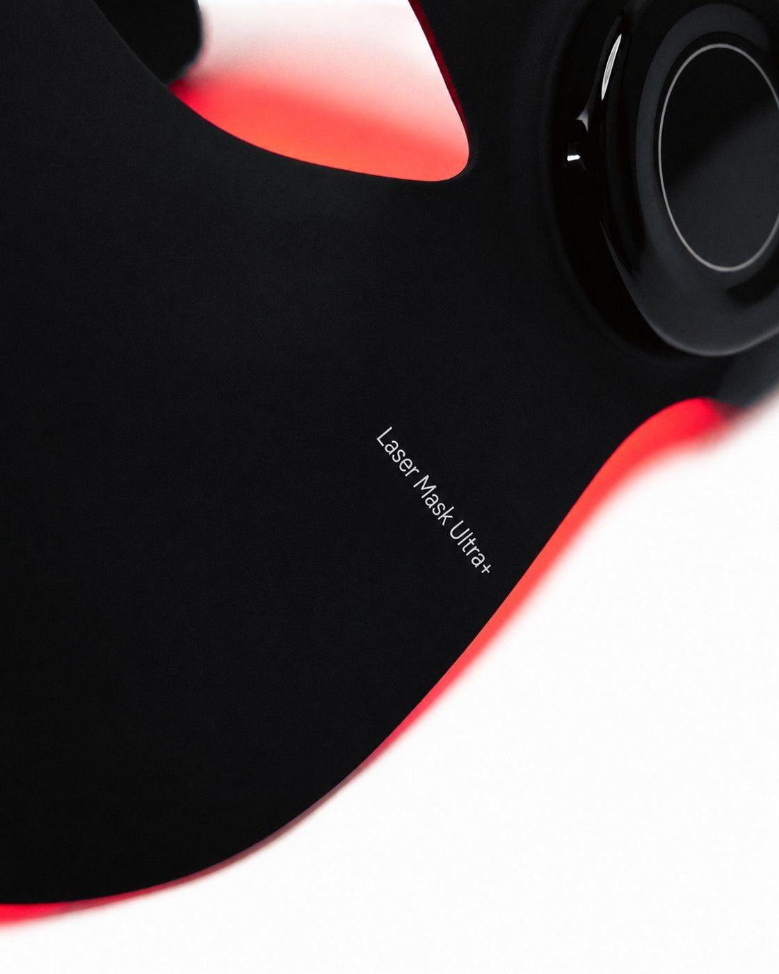 Close-up of the Flowlight Laser Mask Ultra+ showing the model name printed on the black silicone mask and the side control unit.